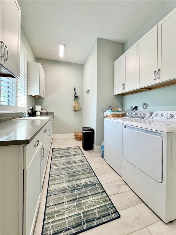 laundry room featuring cabinets, washing machine and dryer, and sink