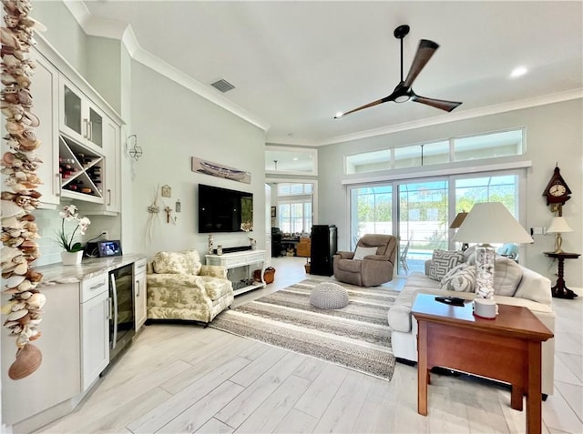 living room with ceiling fan, ornamental molding, and light hardwood / wood-style flooring