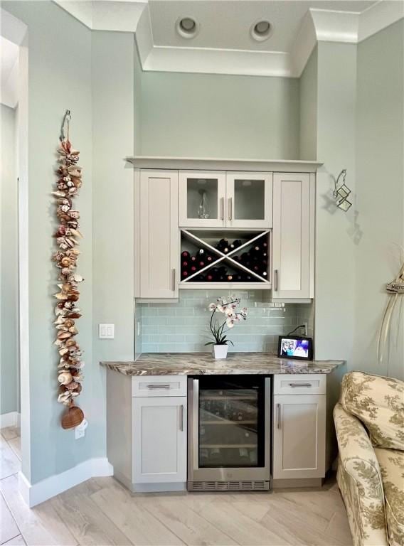 bar with wine cooler, tasteful backsplash, and white cabinets