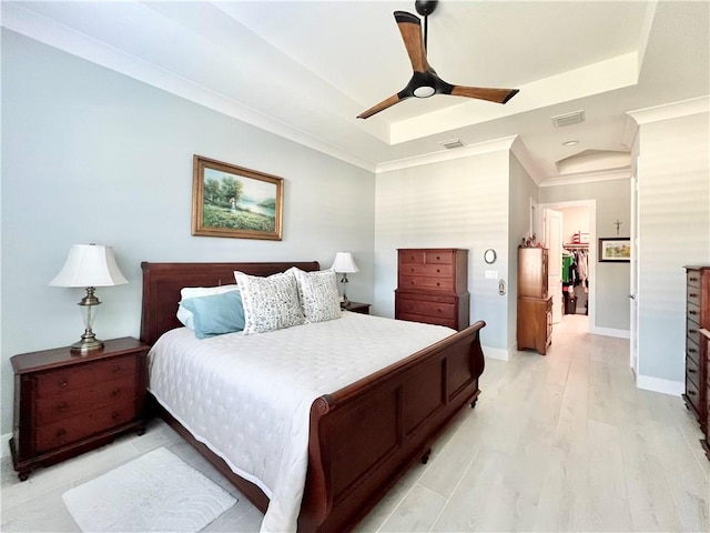 bedroom featuring ceiling fan, ornamental molding, a raised ceiling, and light hardwood / wood-style flooring