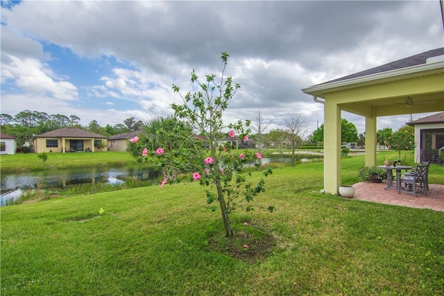 view of yard with a patio area, a water view, and a ceiling fan