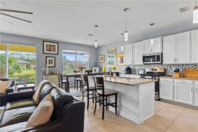 kitchen featuring visible vents, stainless steel appliances, backsplash, and open floor plan