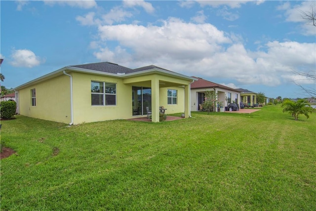 back of property featuring a yard, a patio area, and stucco siding