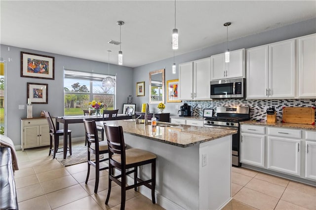 kitchen with appliances with stainless steel finishes, a sink, backsplash, and light tile patterned floors