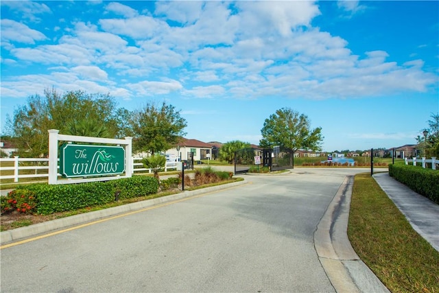 view of road featuring sidewalks, a residential view, a gated entry, and curbs