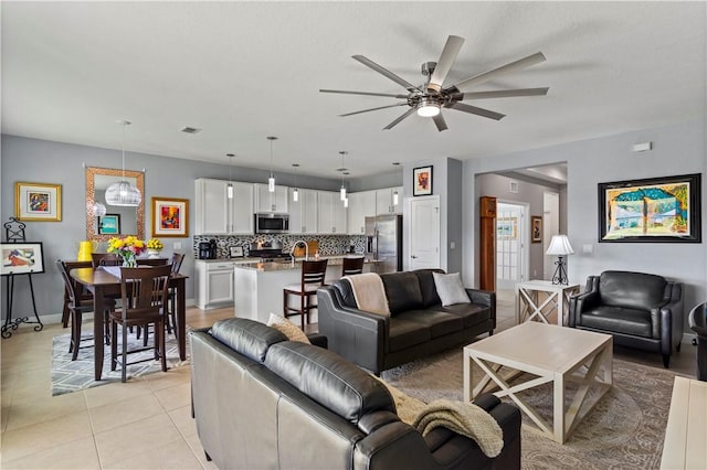 living room with light tile patterned floors, visible vents, baseboards, and a ceiling fan