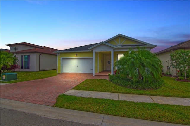 view of front facade with an attached garage, decorative driveway, and a front yard