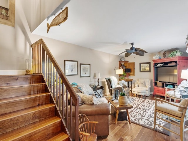 living area featuring stairs, ceiling fan, wood finished floors, and baseboards