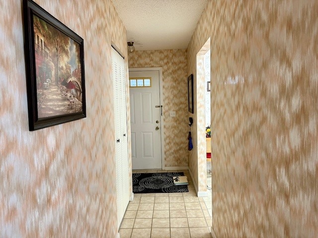 doorway with a textured ceiling and light tile patterned flooring