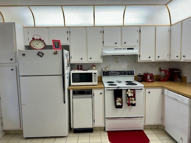 kitchen with white cabinets, light tile patterned floors, and white appliances