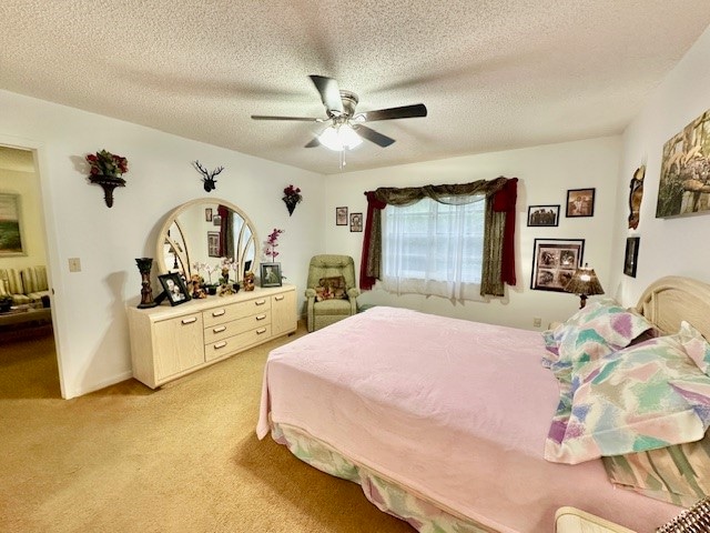 carpeted bedroom featuring a textured ceiling and ceiling fan