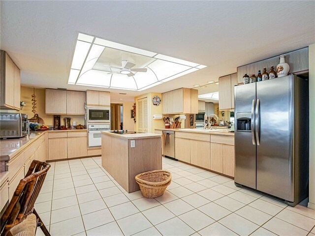 kitchen with stainless steel appliances, a kitchen island, light brown cabinets, kitchen peninsula, and ceiling fan