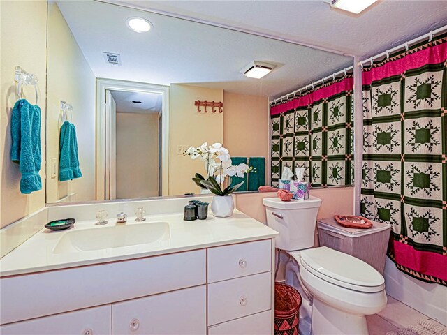 bathroom with curtained shower, vanity, toilet, and a textured ceiling