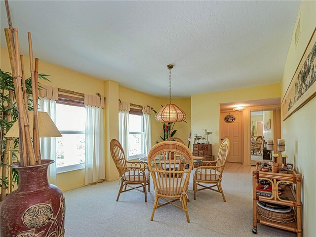 dining area featuring a textured ceiling and light carpet