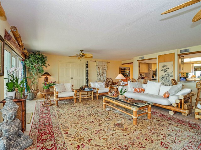 living room with ceiling fan, plenty of natural light, and a textured ceiling