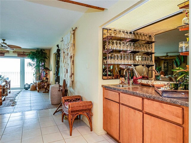 bar with light tile patterned flooring, ceiling fan, and sink