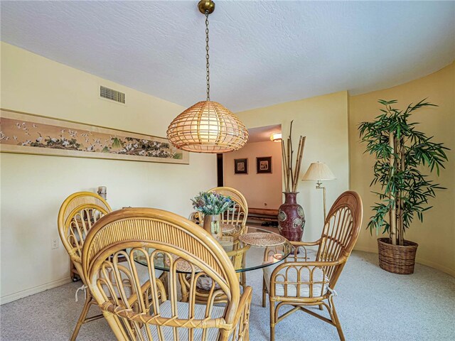 carpeted dining space featuring a textured ceiling