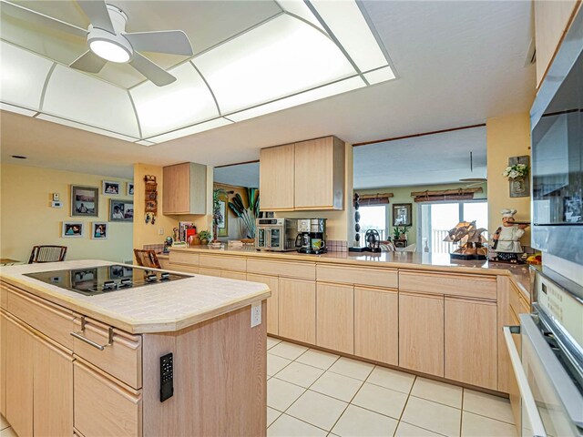 kitchen with light brown cabinetry, kitchen peninsula, oven, and black electric stovetop