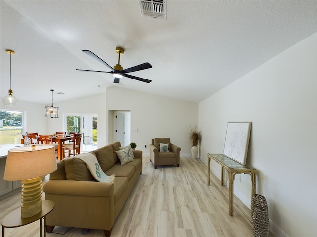 living room with a textured ceiling, ceiling fan, lofted ceiling, and light wood-type flooring