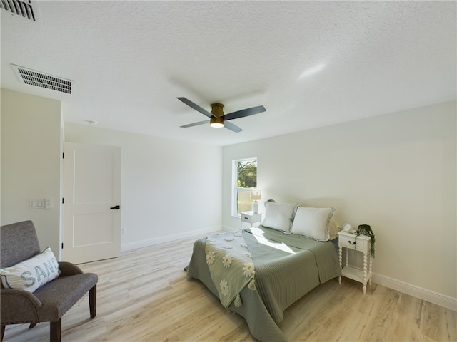 bedroom featuring ceiling fan, light wood-type flooring, and a textured ceiling