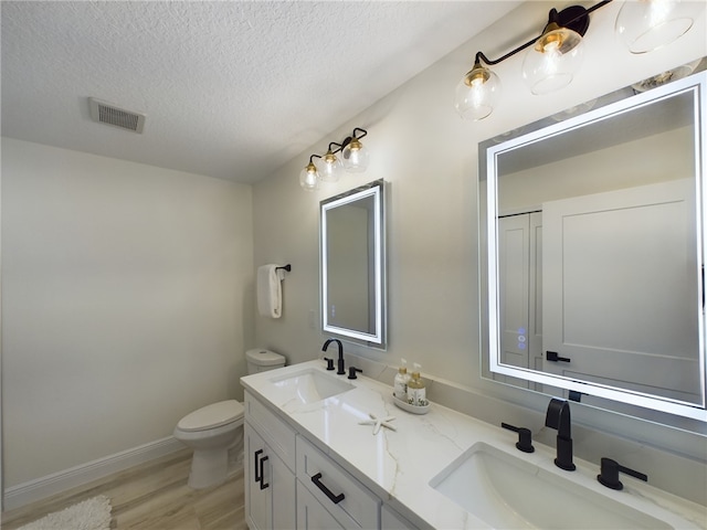 bathroom with vanity, toilet, wood-type flooring, and a textured ceiling