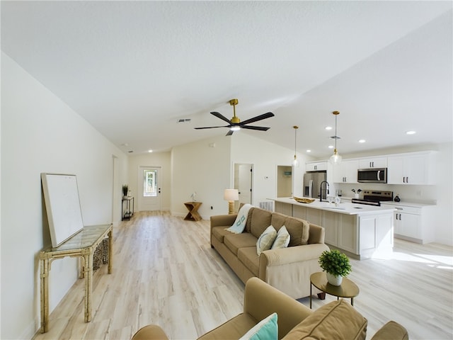 living room with light hardwood / wood-style floors, ceiling fan, lofted ceiling, and sink