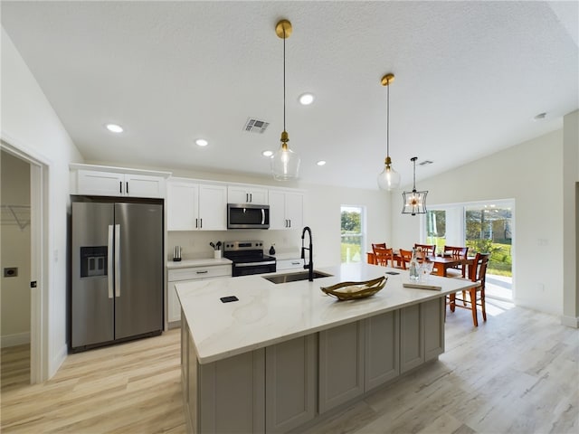 kitchen featuring light stone countertops, appliances with stainless steel finishes, sink, a center island with sink, and white cabinetry