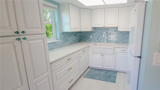 kitchen featuring white cabinets, sink, tasteful backsplash, and white refrigerator