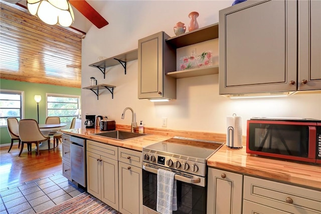 kitchen with wood counters, appliances with stainless steel finishes, open shelves, and a sink