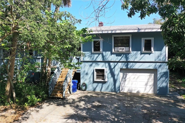 exterior space with a garage, driveway, a chimney, and stairs