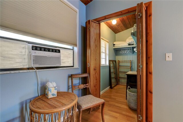 interior space featuring light wood-style flooring, baseboards, vaulted ceiling, and cooling unit