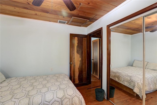 bedroom with a closet, wood ceiling, visible vents, and wood finished floors