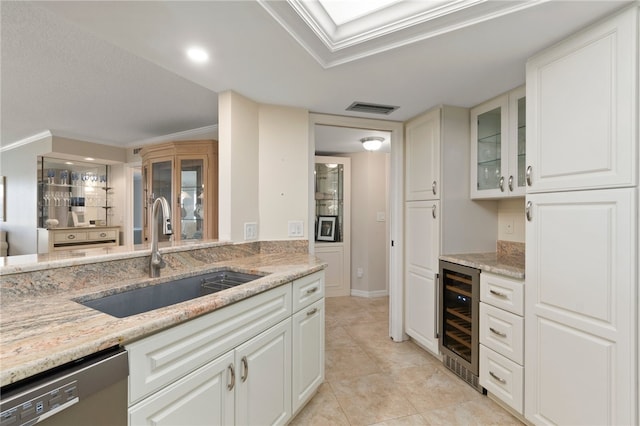 kitchen featuring white cabinetry, sink, light stone countertops, beverage cooler, and crown molding