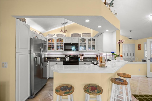 1541 Sabal Ct, Vero Beach, FL 32963 - kitchen featuring black appliances, a peninsula, vaulted ceiling, a breakfast bar, and glass insert cabinets