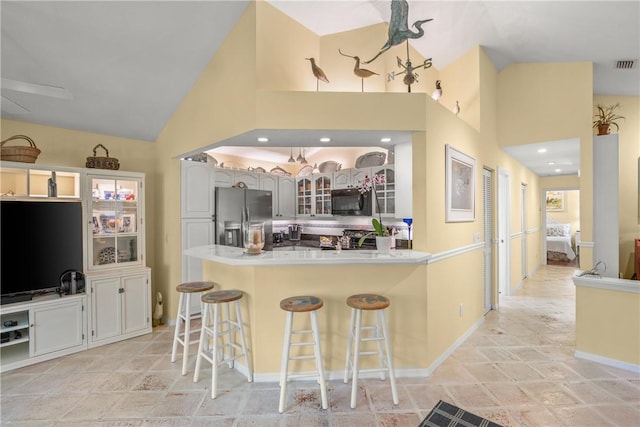 1541 Sabal Ct, Vero Beach, FL 32963 - kitchen featuring stainless steel fridge with ice dispenser, black microwave, high vaulted ceiling, a peninsula, and glass insert cabinets