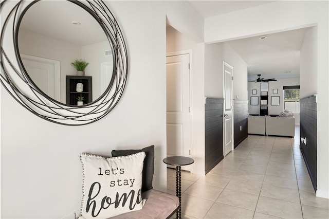 hallway featuring light tile patterned flooring and tile walls