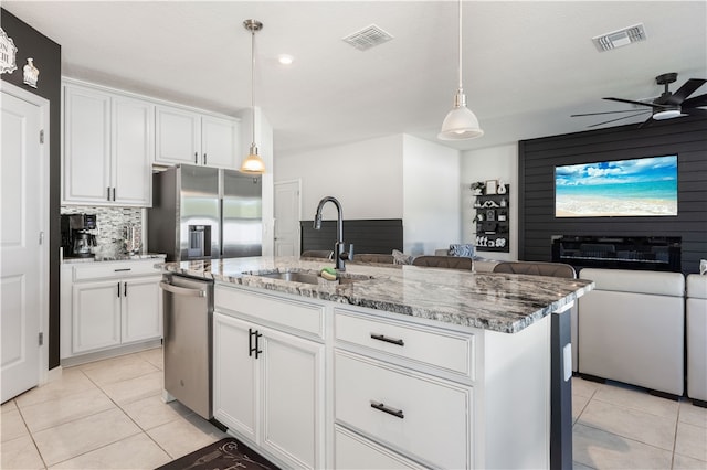 kitchen featuring white cabinetry, sink, stainless steel appliances, an island with sink, and pendant lighting