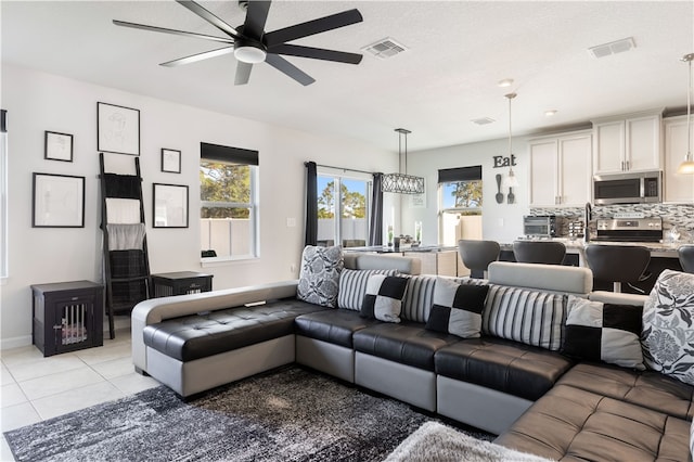 tiled living room featuring ceiling fan with notable chandelier