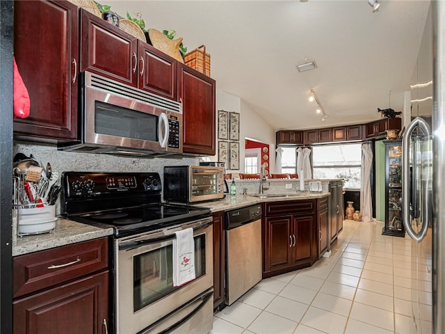 kitchen with track lighting, light stone counters, stainless steel appliances, sink, and light tile patterned flooring