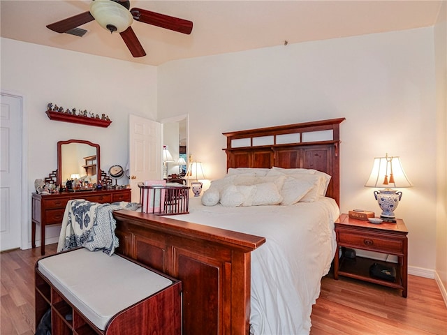 bedroom featuring a ceiling fan, vaulted ceiling, visible vents, and light wood-type flooring