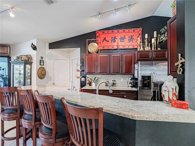 kitchen featuring kitchen peninsula, stainless steel fridge, and lofted ceiling