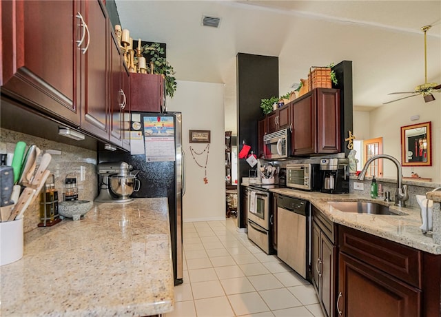 kitchen with sink, ceiling fan, light tile patterned floors, light stone countertops, and appliances with stainless steel finishes