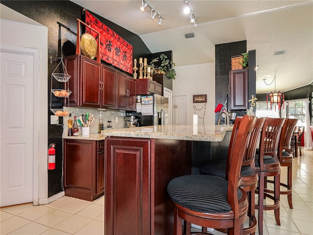 kitchen with a breakfast bar area, kitchen peninsula, stainless steel fridge with ice dispenser, and lofted ceiling