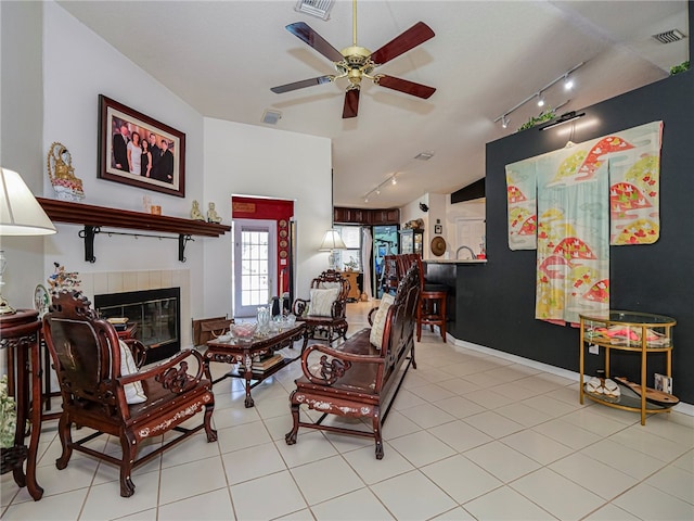 living room with a tile fireplace, ceiling fan, light tile patterned flooring, and rail lighting