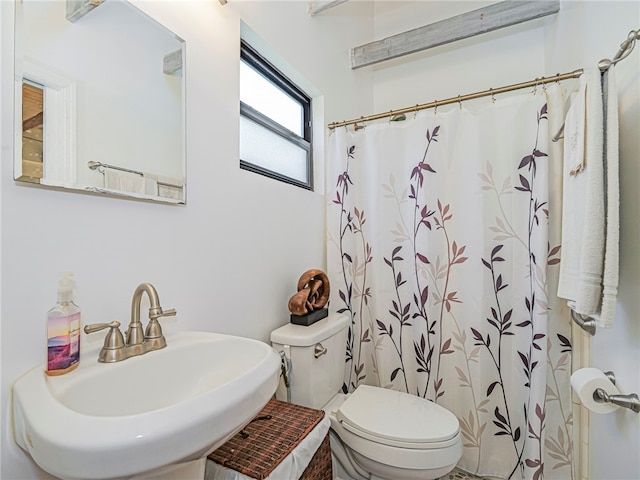 bathroom featuring a sink, curtained shower, and toilet