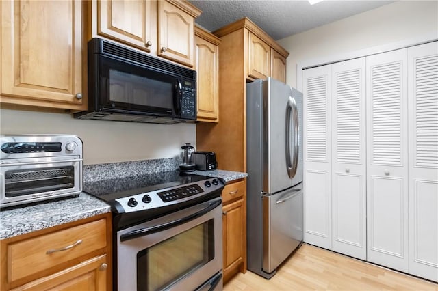 25 Plantation Dr Unit 201, Vero Beach, FL 32966 - kitchen with stainless steel appliances, light wood-style floors, and light stone counters