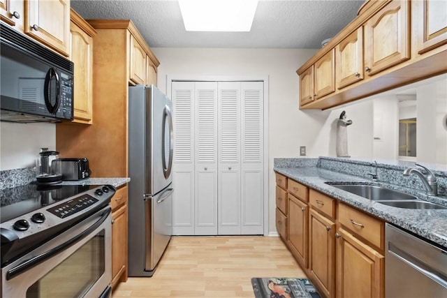 25 Plantation Dr Unit 201, Vero Beach, FL 32966 - kitchen featuring stainless steel appliances, a sink, light wood finished floors, light stone countertops, and a textured ceiling