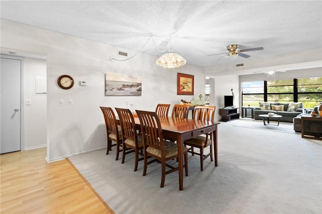 25 Plantation Dr Unit 201, Vero Beach, FL 32966 - dining space with a textured ceiling, ceiling fan, baseboards, a chandelier, and light wood-style flooring