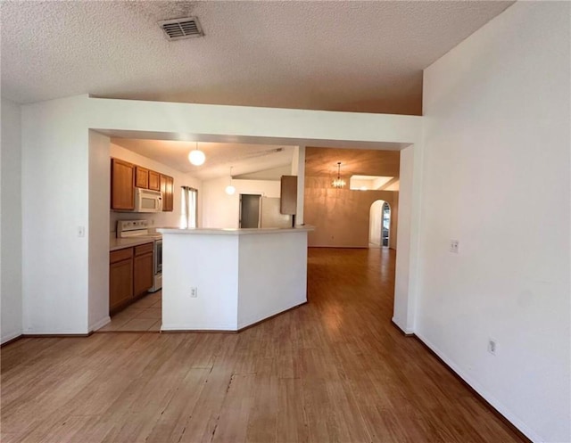 kitchen featuring range with electric stovetop, white microwave, brown cabinetry, light wood-style floors, and arched walkways