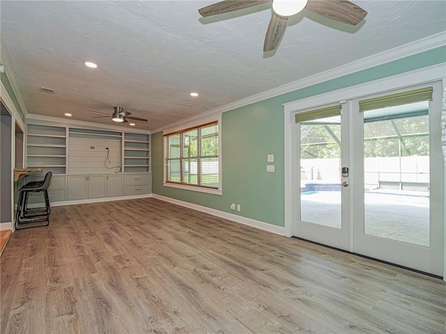 unfurnished living room featuring a textured ceiling, crown molding, and ceiling fan